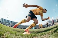 a man kicking a soccer ball on top of a field with people in the background