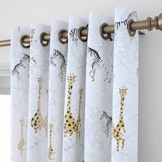 curtains with giraffes and zebras on them hanging from a curtain rod