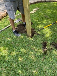 a man is digging in the ground with a wooden pole and measuring tape on it