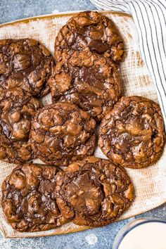 chocolate cookies on a plate next to a glass of milk and a striped napkin with a cloth