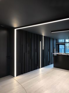 an empty room with black walls and white flooring is lit up by led lights