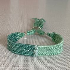 a close up of a knitted bracelet on a white tablecloth with green beads