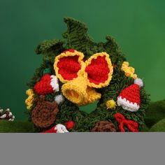 a crocheted christmas wreath with red and yellow glasses, pine cones, and acorns