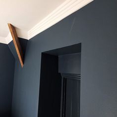 the corner of a room painted blue with a wooden shelf above it and a mirror on the wall