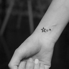 a small black star tattoo on the left inner wrist, and an outline of three stars