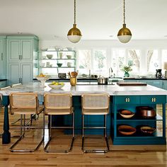 a kitchen with blue cabinets and white counter tops, two pendant lights over the island