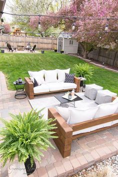 a patio with couches and tables in the middle of it, surrounded by grass