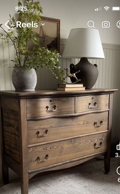 a wooden dresser with two vases and a lamp on it's side table