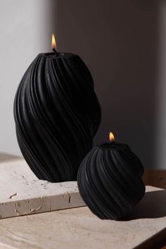 two black candles sitting on top of a wooden table