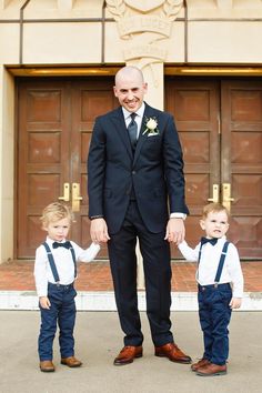 a man in a suit holding hands with two small boys