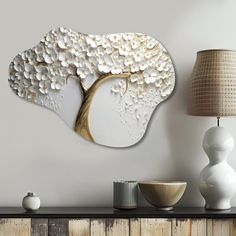 a wall mounted art piece with white flowers and a tree on the back of it