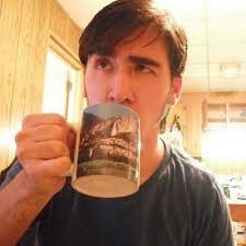 a man is drinking from a coffee mug