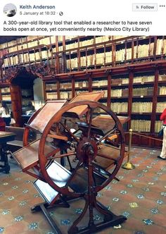 an old spinning wheel in the middle of a library with bookshelves behind it