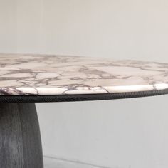 a marble topped table sitting on top of a hard wood floor next to a white wall