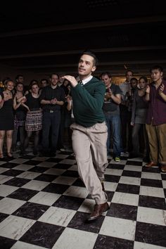 a man standing on top of a checkered floor in front of a group of people