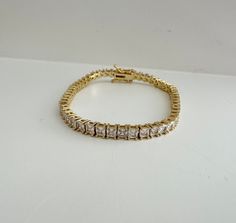 "Perfect worn on its own or layered with our other bracelets. 18k gold filled. Cubic zirconia 7\" length *18k gold filled is a more affordable alternative to solid gold jewelry. Gold filled is a layer of gold bonded onto a base metal with heat and pressure that contains 100+ times more gold than gold plated jewelry.  *It is very durable and tarnish resistant.  *With proper care, gold filled jewelry can last several years. Avoid contact with harsh chemicals, perfumes, water, etc.  *Gold filled jewelry can be worn by people with sensitive skin because it is hypoallergenic, lead free and nickel free." Gold Rectangular Tennis Bracelet As A Gift, Classic Rectangular Gold Tennis Bracelet, Luxury Gold Rectangular Tennis Bracelet, Gold-tone 14k Gold Jubilee Bracelet, Gold-tone 14k Gold Jubilee Chain Bracelet, Gold-tone Rectangular Links Bracelet, Gold-tone Stainless Steel Jubilee Bracelet, Gold-tone Cubic Zirconia Bracelet, Gold Tennis Bracelet