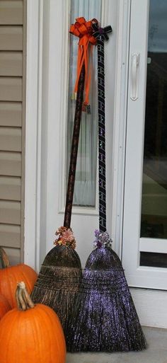 two brooms sitting on the front porch next to pumpkins