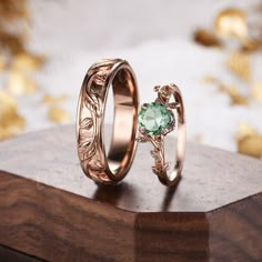 two gold wedding rings with an aqua stone in the center on top of a wooden box