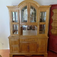 a wooden china cabinet sitting on top of a hard wood floor