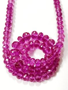 purple beads are arranged on a white surface