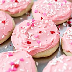 pink frosted cookies with sprinkles on a baking sheet, ready to be baked