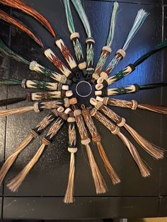 a clock made out of many different types of yarns and wood sticks on a wall