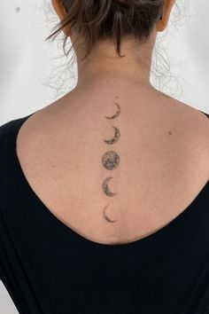 the back of a woman's neck with three moon tattoos on it