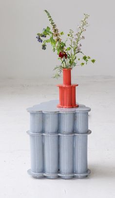 there is a vase with flowers in it on top of two barrels that are stacked up