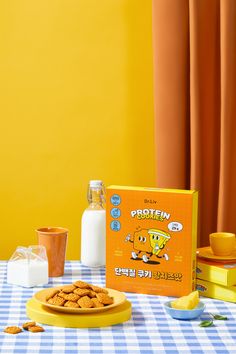 an orange box sits next to a plate of cookies and milk on a checkered table cloth