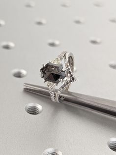 a diamond ring sitting on top of a piece of metal with holes in the background