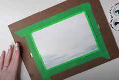 someone is making a photo frame out of cardboard and green construction paper on the table