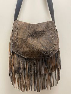 Safari tan full grain lambskin leather from New Zealand has hand whipstitched details, brass colored buckle and grommets on strap. This large sized crossbody fringed bag has lots of storage and zippered pocket on the backside of the bag. Due to lighting used during photography, actual finishes may vary from imagery. Exterior: Magnetic closure. Zip compartment on back. Interior: Satin lined. Center zip compartment. Dimensions: 15W x 14H x 2D (6-7" fringe) Adjustable Strap: 19-21 inch drop. Made i Leather Hobo Bag Crossbody For Festival, Leather Crossbody Hobo Bag For Festivals, Leather Fringe Satchel Shoulder Bag, Leather Satchel With Fringe For Travel, Leather Fringe Satchel For Everyday, Leather Travel Satchel With Fringe, Everyday Leather Fringe Satchel, Leather Hobo Bag With Tassels In Crossbody Style, Brown Leather Fringe Shoulder Bag