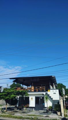 a white building sitting on the side of a road next to power lines and telephone poles