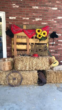 hay bales stacked on top of each other in front of a building with sunflowers