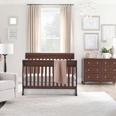 a baby's room with a crib, dresser and chair