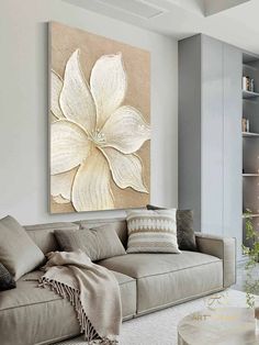 a living room with a couch, coffee table and large flower painting on the wall