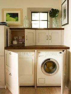 a washer and dryer in a small room with cabinets on the wall behind them