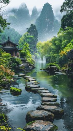 a river with stepping stones in the middle and mountains in the backgrouds