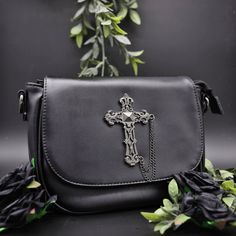 Our stunning black vegan leather cross body bag with brush metal cross with chain detailing design.  Comes with long detachable strap,  Beautifully crafted Cross Body Design with brushed Metal Cross Centre Piece with detachable long adjustable strap, magnetic opening, zip opening on the top and comes fully lined with black cloth. There is a pocket also on the back of the bag for anything you need to reach in a hurry.   Measurements  H=16cm W=24cm D=9cm Gothic Black Shoulder Bag With Adjustable Strap, Black Gothic Crossbody Bag, Gothic Black Crossbody Bag, Black Grunge Crossbody Shoulder Bag, Gothic Shoulder Bag For Everyday Use, Gothic Black Bags For Alternative Fashion, Gothic Black Bag For Alternative Fashion, Gothic Shoulder Bag For Alternative Fashion, Black Gothic Shoulder Bag For Gift