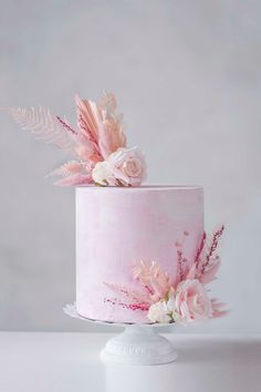 a pink cake decorated with flowers and feathers