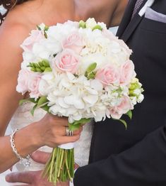 the bride and groom are holding bouquets of white and pink flowers in their hands