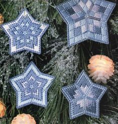 four crocheted snowflakes hanging from a pine tree with lights in the background