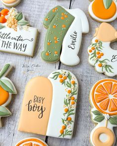 decorated cookies with baby boy names and oranges on them are laid out in rows