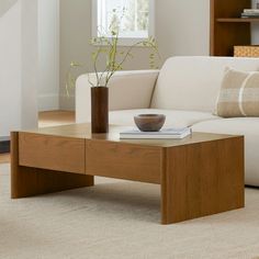 a living room with a white couch and wooden coffee table in front of a window