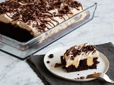 a piece of cake on a plate next to a glass dish with chocolate frosting