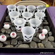 there are many cups with faces painted on them and balls in the middle of it