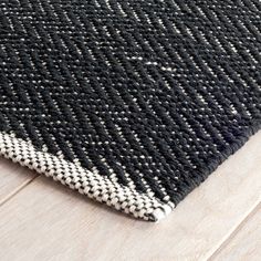 a black and white rug is laying on the floor next to a wood flooring