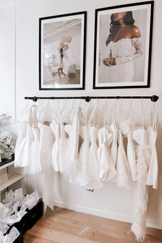 two framed pictures hang on the wall next to wedding dresses