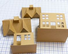 three cardboard model houses sitting on top of a piece of paper next to each other