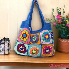 a crocheted purse sitting on top of a wooden table next to a potted plant